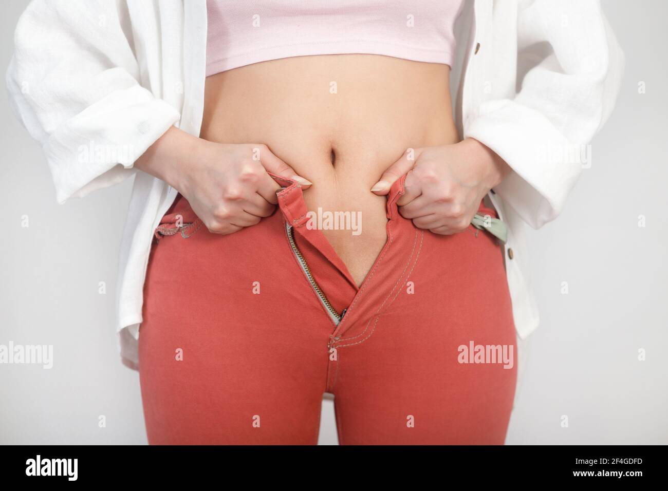 Gros plan de la graisse d'estomac la femme ne peut pas attacher une fermeture à glissière sur les jeans. Régime, poids corporel, concept d'obésité. Banque D'Images