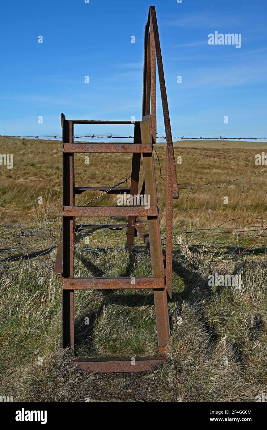 Une échelle rouillée enserre une clôture barbelée à la campagne sentier public Banque D'Images