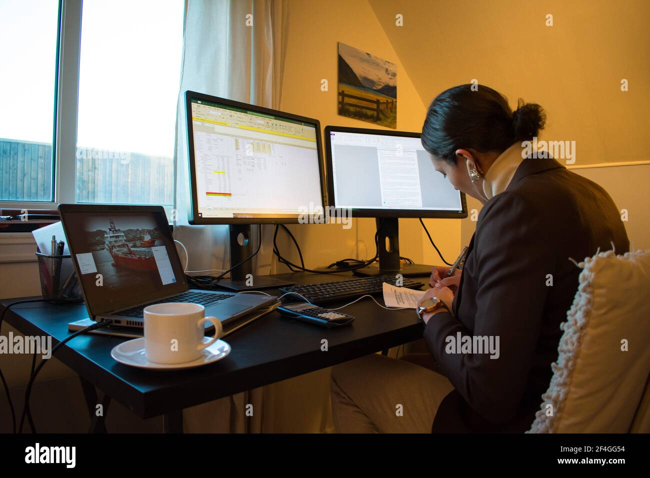 Femme travaillant à domicile dans son bureau à domicile avec du café - poste de travail à plusieurs moniteurs Banque D'Images