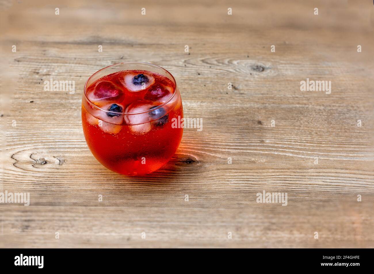 cocktail de soda et vodka rouge avec framboise et myrtille en forme de coeur glace sur table en bois Banque D'Images