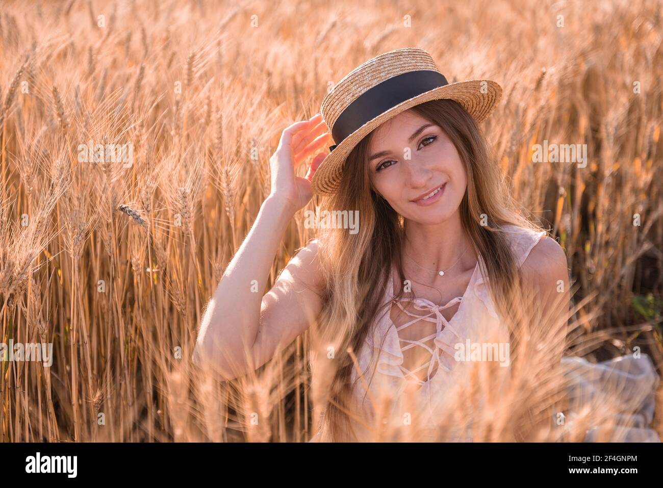 Jeune femme blonde en chapeau de paille sur le fond d'un champ d'épillets dorés de blé, seigle. Gros plan portrait d'une belle fille aux yeux bruns. W Banque D'Images