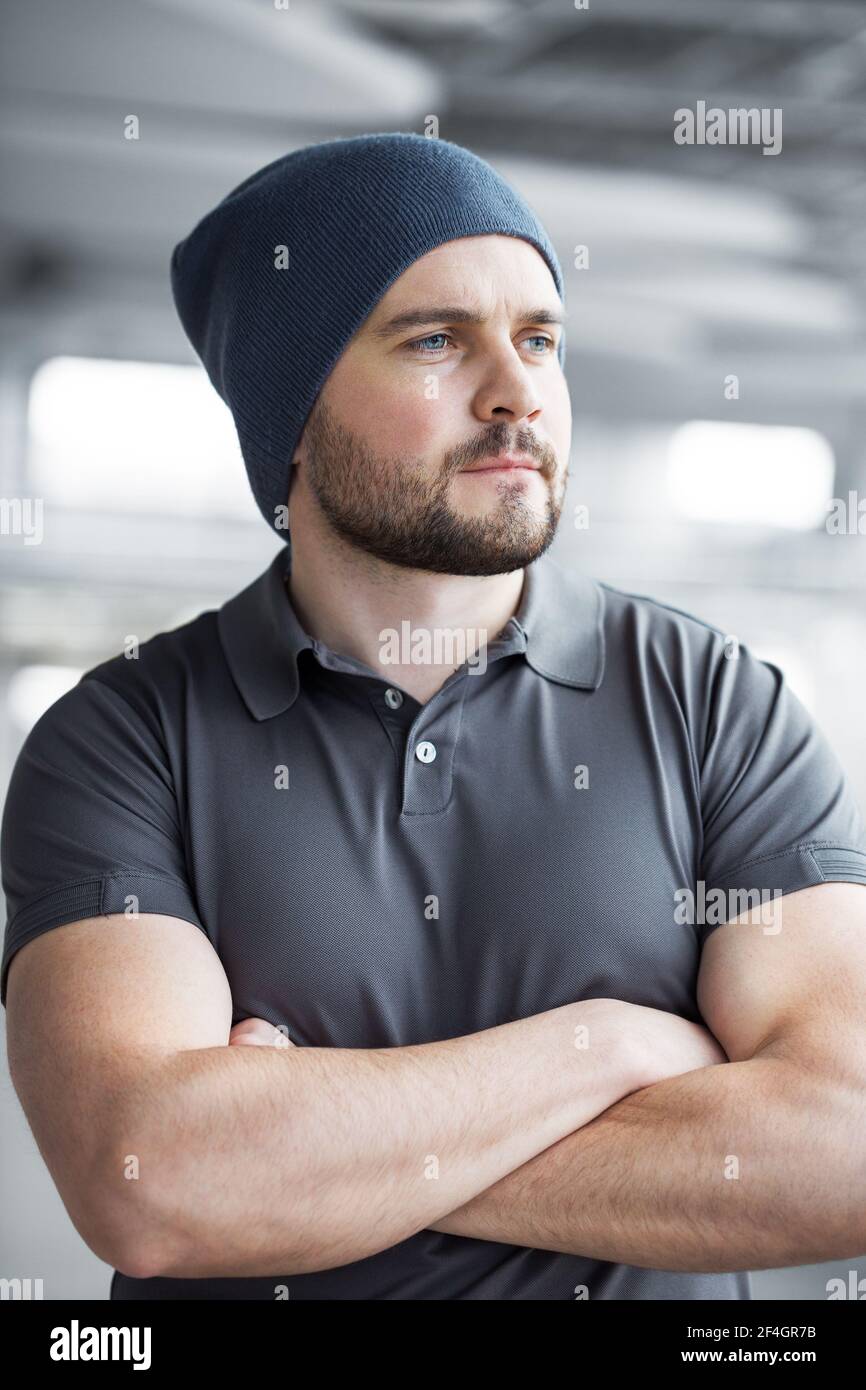 Portret un beau jeune homme avec une barbe qui regarde par la fenêtre. Image d'un homme heureux portant des vêtements habillés sur fond gris. Banque D'Images
