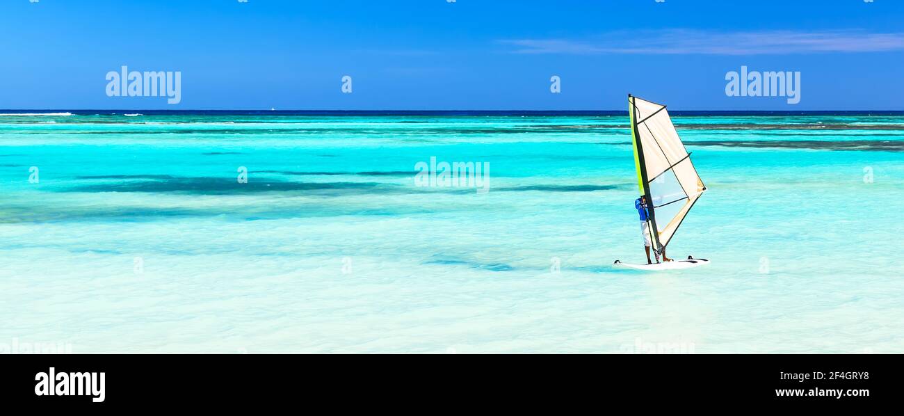 Panorama de la belle plage avec planche à voile sur la mer sur fond bleu ciel. Planche à voile sur fond de paysage de plage et bleu clair Banque D'Images