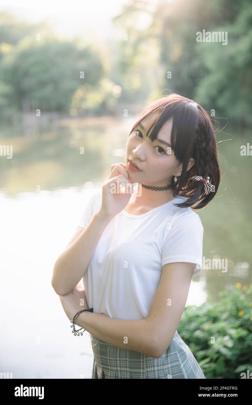 portrait de fille asiatique avec chemise blanche et jupe regardant en plein air urbain style vintage film Banque D'Images