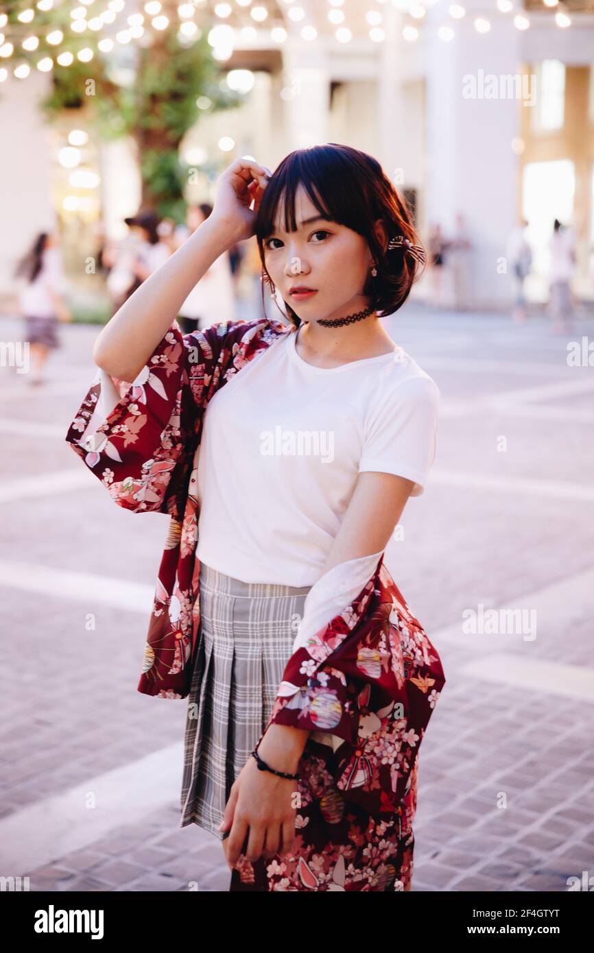 portrait de fille asiatique avec chemise blanche et jupe regardant en plein air urbain style vintage film Banque D'Images