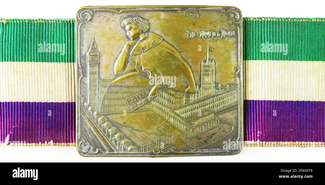 Boucle en laiton avec une figure féminine fantôme, portant un panneau « votes pour les femmes », survolant les chambres du Parlement britannique, gravé « la Maison hantée » et attaché à une ceinture en ruban vert, blanc et violet, conçue par David Wilson pour l'Union sociale et politique des femmes, Royaume-Uni, le 6 août 1908. Photographie par Emilia van Beugen. () Banque D'Images