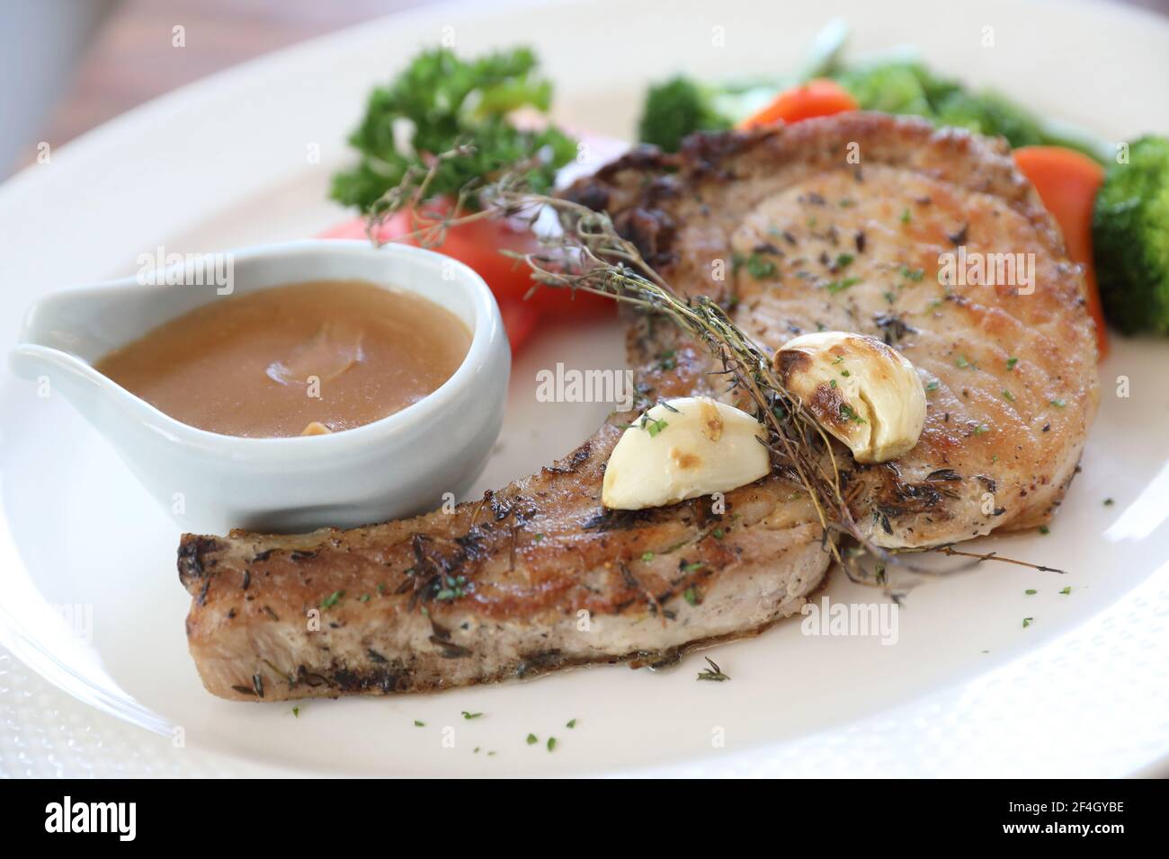 hache de porc grillée avec légumes sur plat avec table en bois arrière-plan Banque D'Images