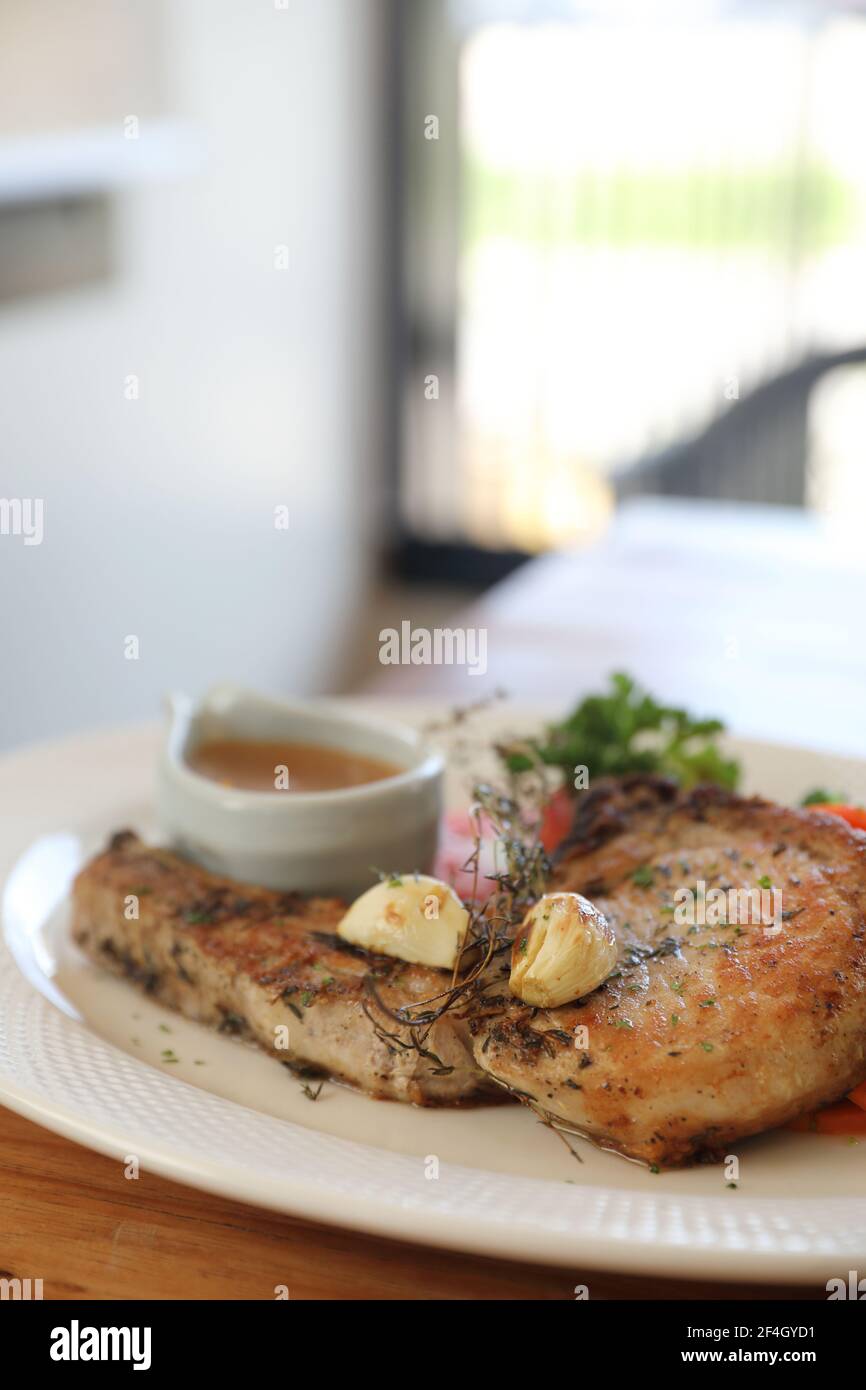 hache de porc grillée avec légumes sur plat avec table en bois arrière-plan Banque D'Images