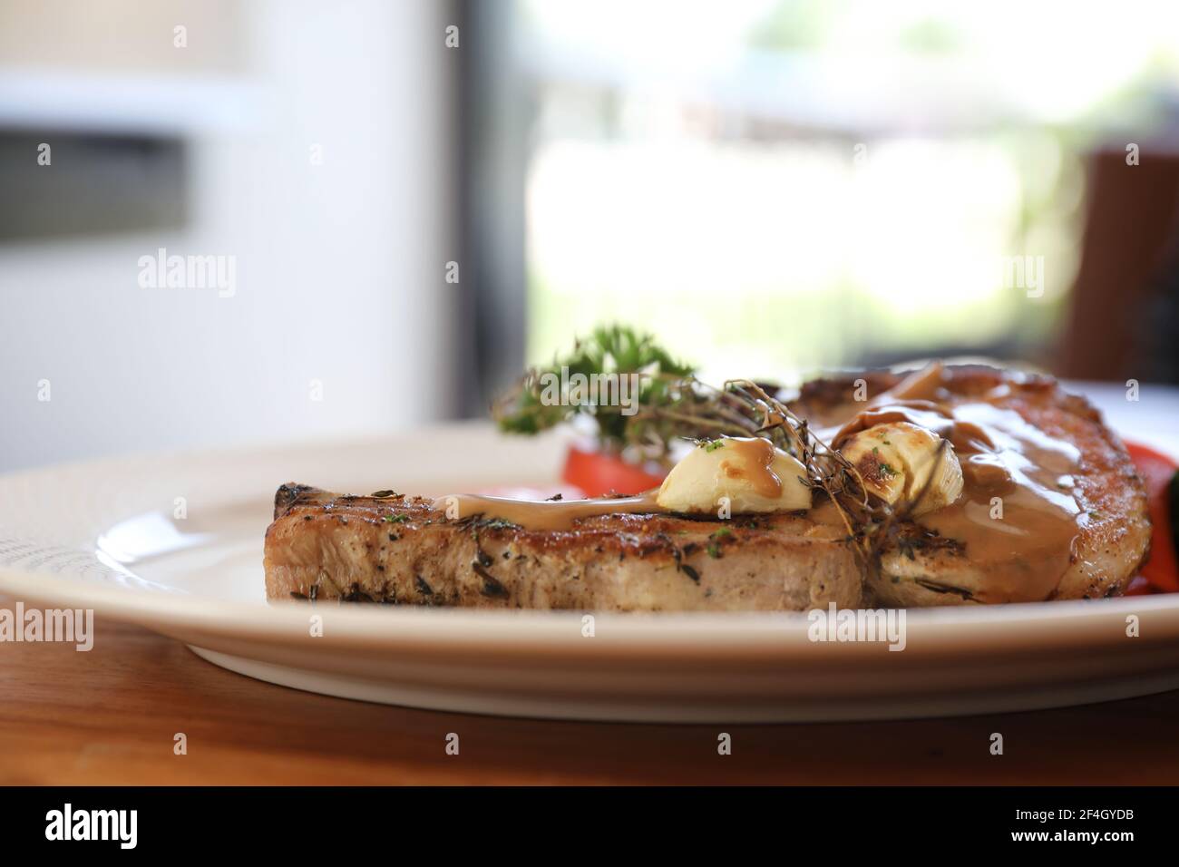 hache de porc grillée avec légumes sur plat avec table en bois arrière-plan Banque D'Images