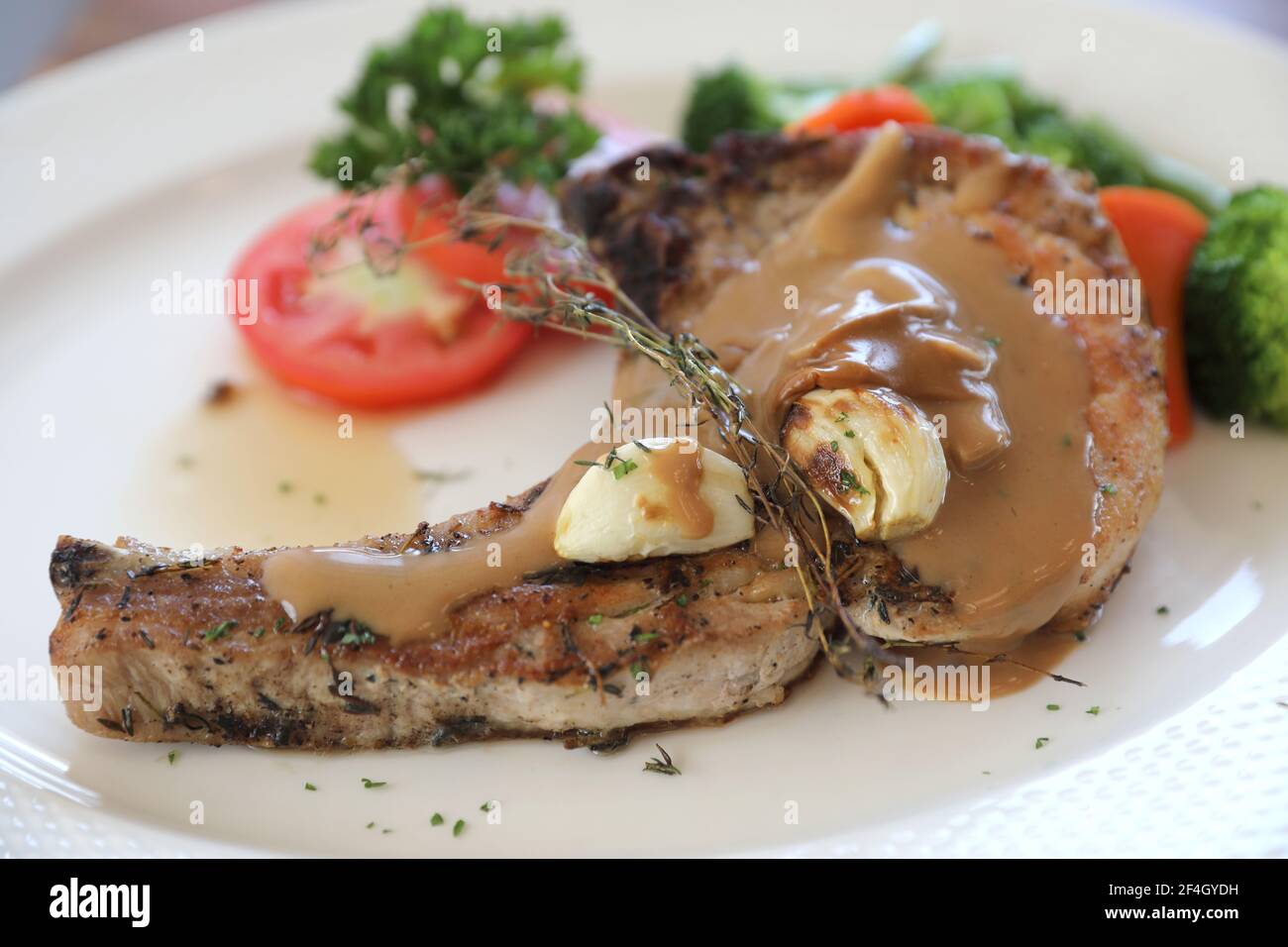 hache de porc grillée avec légumes sur plat avec table en bois arrière-plan Banque D'Images