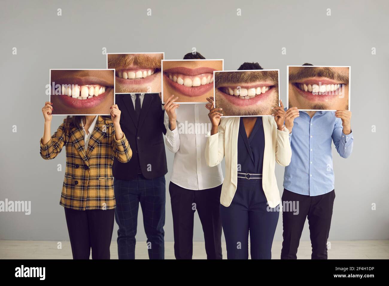 Groupe de personnes diverses se cachant derrière de grandes photos amusantes de sourires heureux et séduisants Banque D'Images