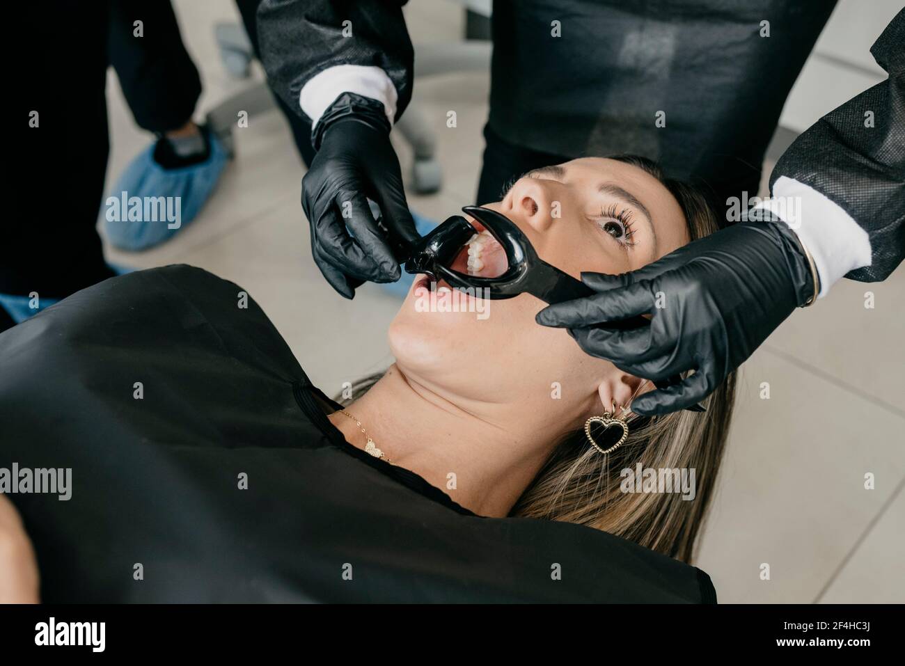 Grand angle de récolte dentiste méconnaissable avec enrouleurs examinant les dents de la cliente pendant le traitement dentaire dans la clinique contemporaine Banque D'Images Grand angle de récolte dentiste méconnaissable avec enrouleurs examinant les dents de la cliente pendant le traitement dentaire dans la clinique contemporaine Banque D'Images
