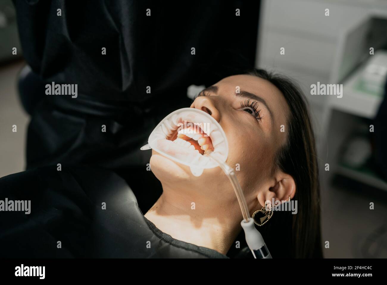 Croquez un dentiste méconnaissable tout en traitant les dents de la femme avec de la salive éjecteur et enrouleur dans la bouche Banque D'Images Croquez un dentiste méconnaissable tout en traitant les dents de la femme avec de la salive éjecteur et enrouleur dans la bouche Banque D'Images