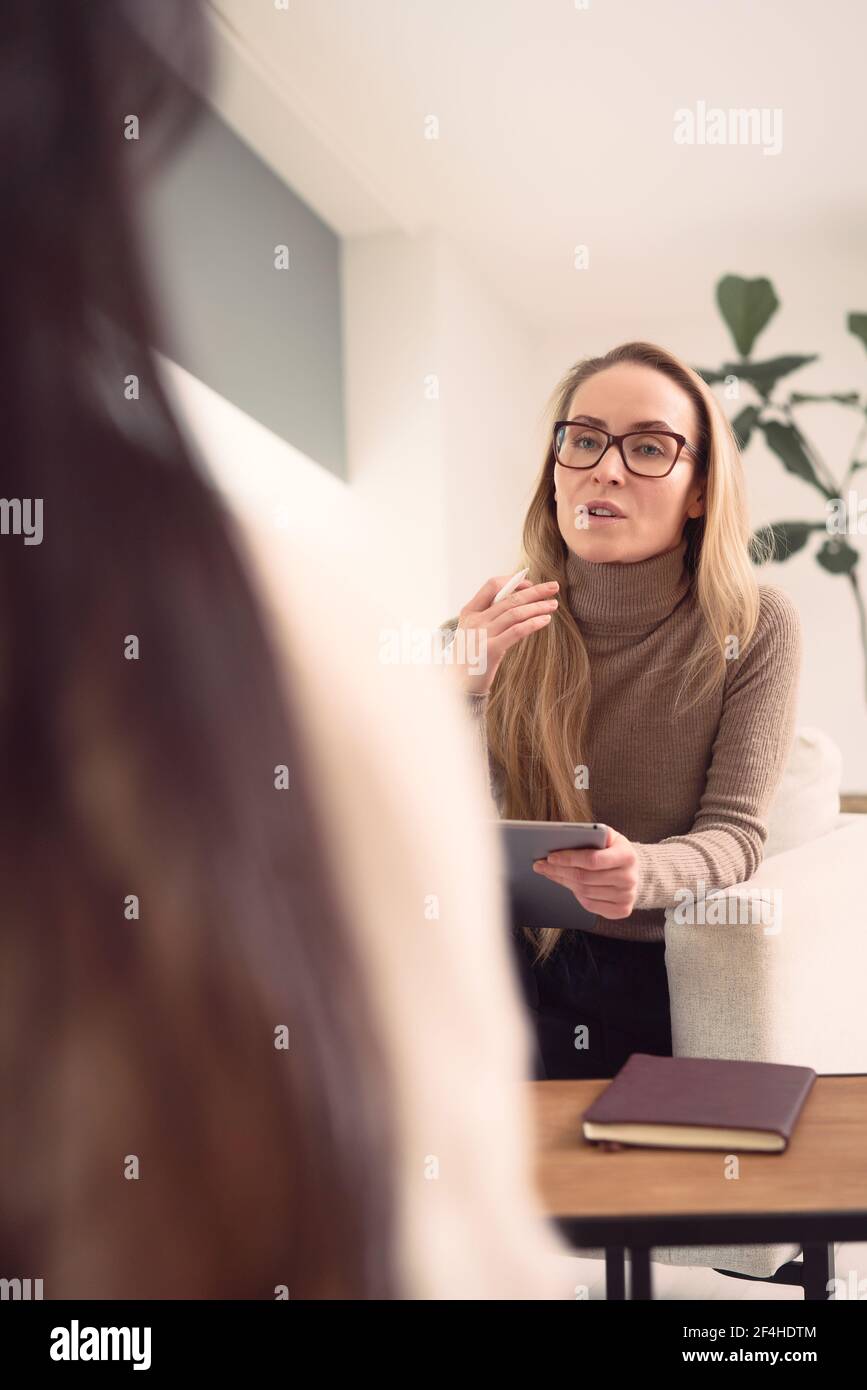 Femme conseillère assise dans un fauteuil et donnant des conseils à méconnaissable client pendant un rendez-vous de psychothérapie Banque D'Images