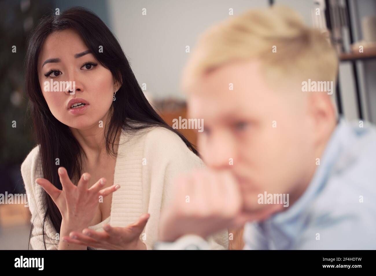 Malheureuse femme asiatique prenant à l'homme indifférent pendant la séance de thérapie dans le bureau du psychologue Banque D'Images