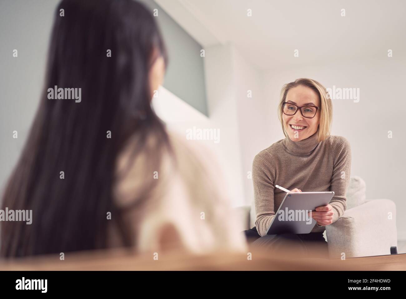 Vue latérale du médecin spécialiste masculin en uniforme de protection, gants en latex et écran facial vaccinant la patiente afro-américaine en clinique pendant Banque D'Images