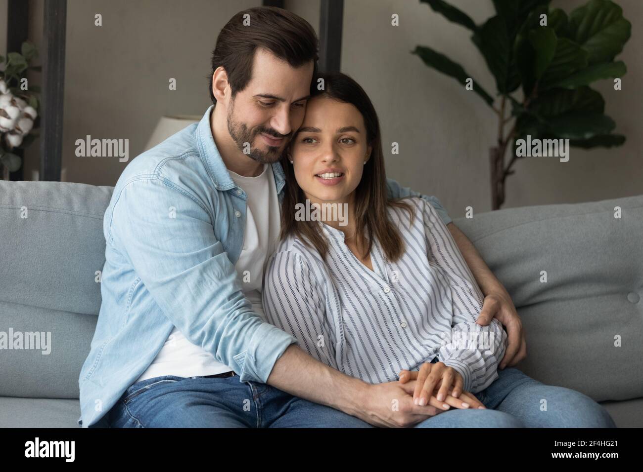 Un jeune couple heureux et aimant se serrer, se détendre sur un canapé ensemble Banque D'Images