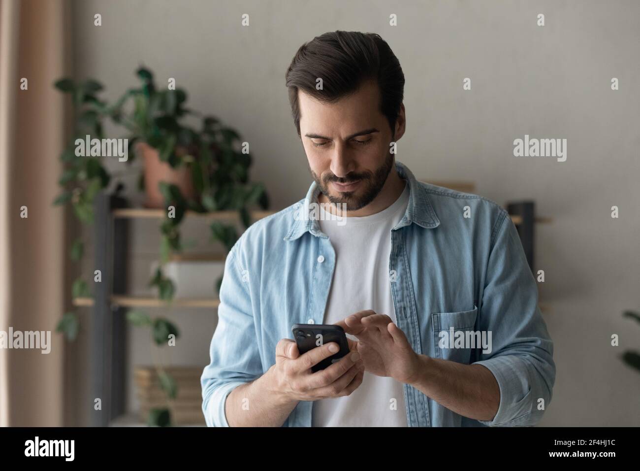Gros plan homme concentré regardant l'écran du téléphone, debout Banque D'Images
