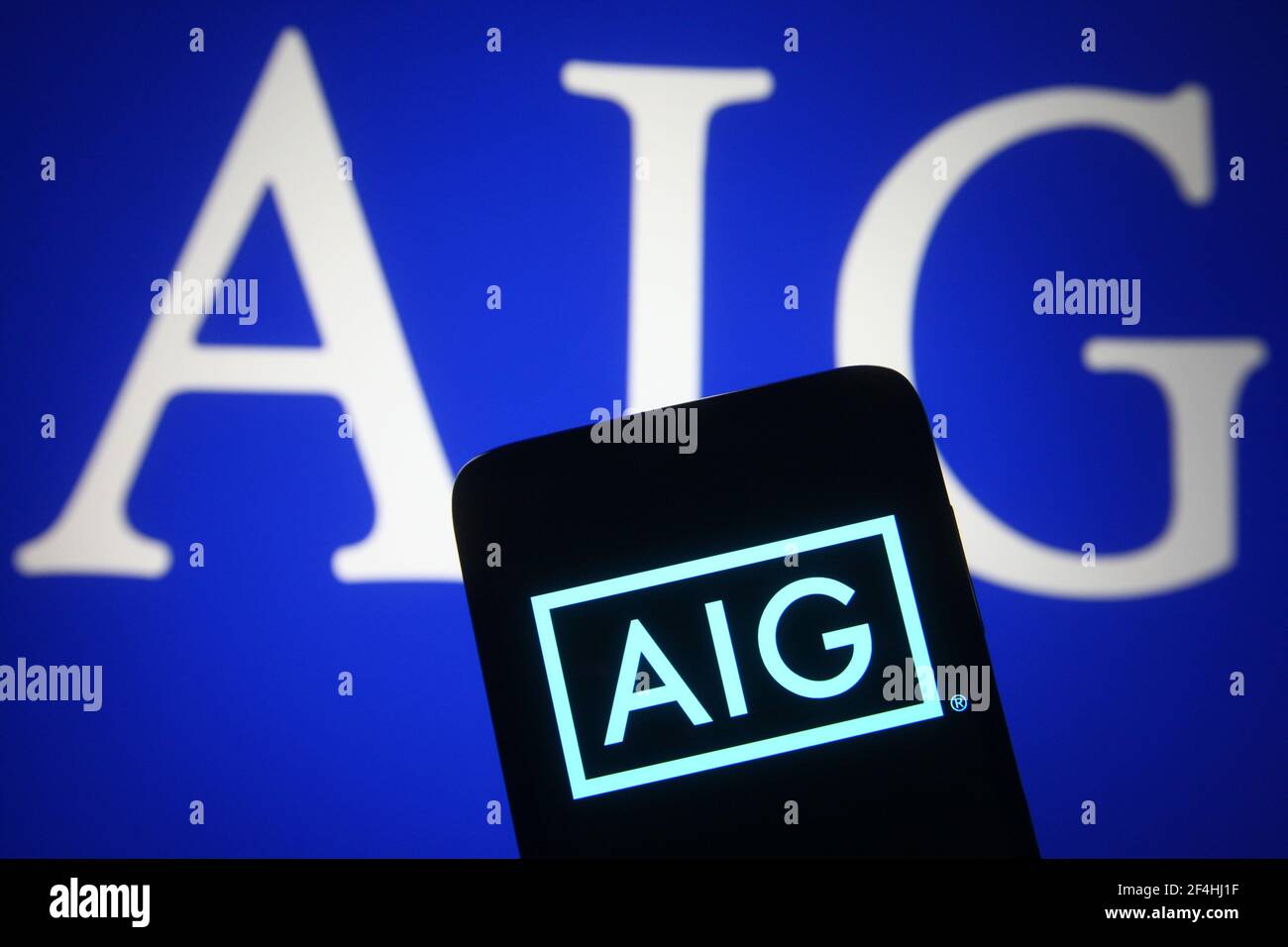 Dans cette illustration, un logo d'American International Group (AIG) d'une société de finance et d'assurance américaine est visible sur un smartphone et un écran de pc. Banque D'Images