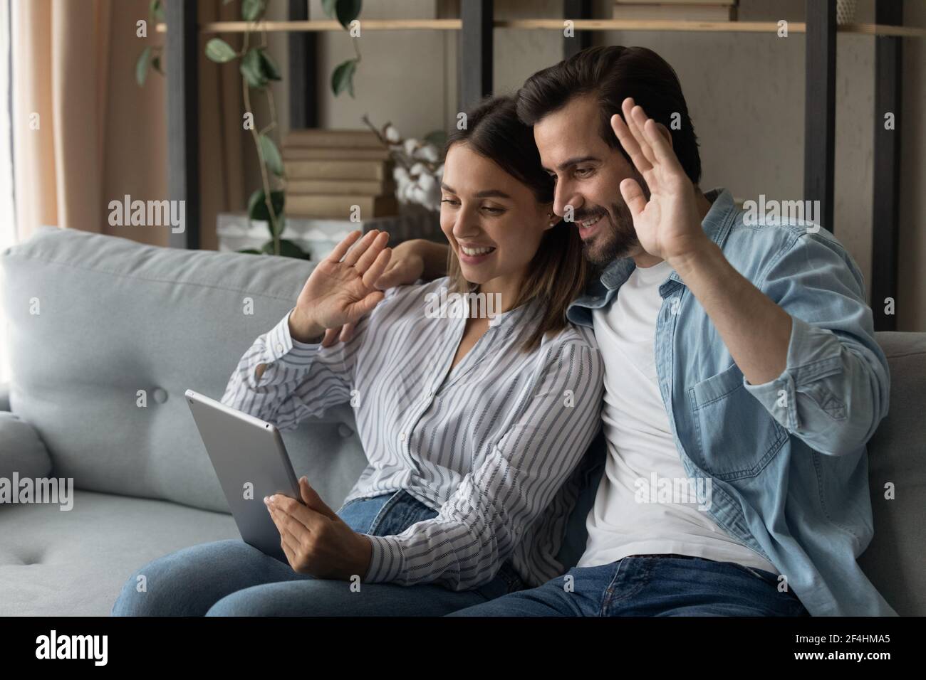 Gros plan couple souriant utilisant une tablette, en se faisant passer les mains, en visiophant Banque D'Images