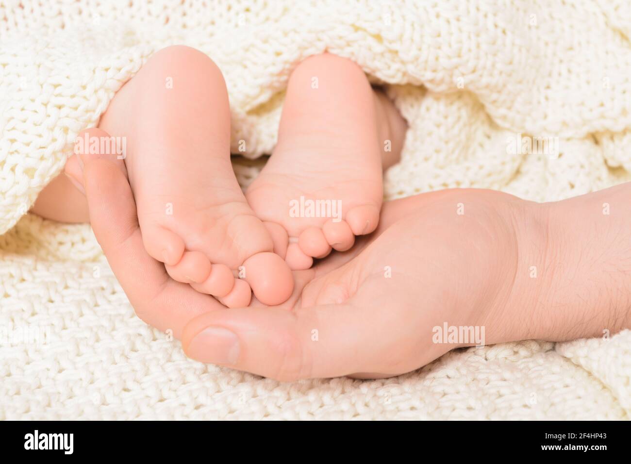 Les pieds de bébé sur la main d'un homme avec un arrière-plan doux, gros plan Banque D'Images