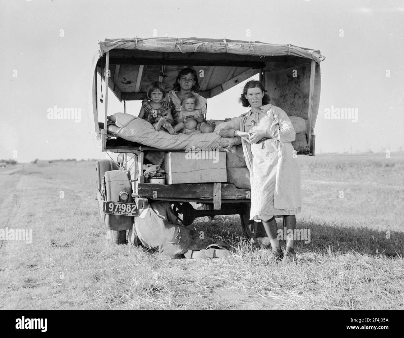 Famille entre Dallas et Austin, Texas. Les gens ont quitté leur maison et leurs connexions dans le sud du Texas, et espèrent atteindre le delta de l'Arkansas pour le travail dans les champs de coton. Personnes sans pénitence. Pas de nourriture et trois gallons de gaz dans le réservoir. Le père tente de réparer un pneu. Trois enfants. Le père dit: «c'est dur, mais la vie est dure de toute façon que vous le prenez». Août 1936. Photo de Dorothea Lange. Banque D'Images