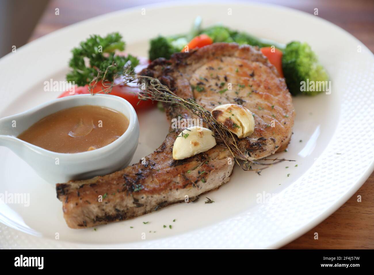 hache de porc grillée avec légumes sur plat avec table en bois arrière-plan Banque D'Images