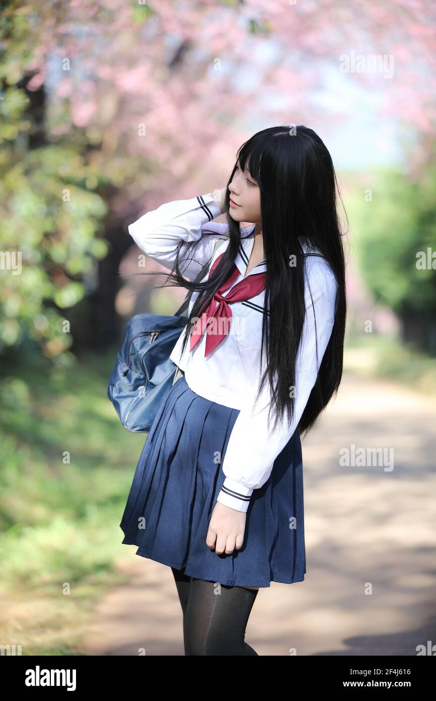 Robe de fille d'école japonaise avec sakura fleur nature allée Banque D'Images