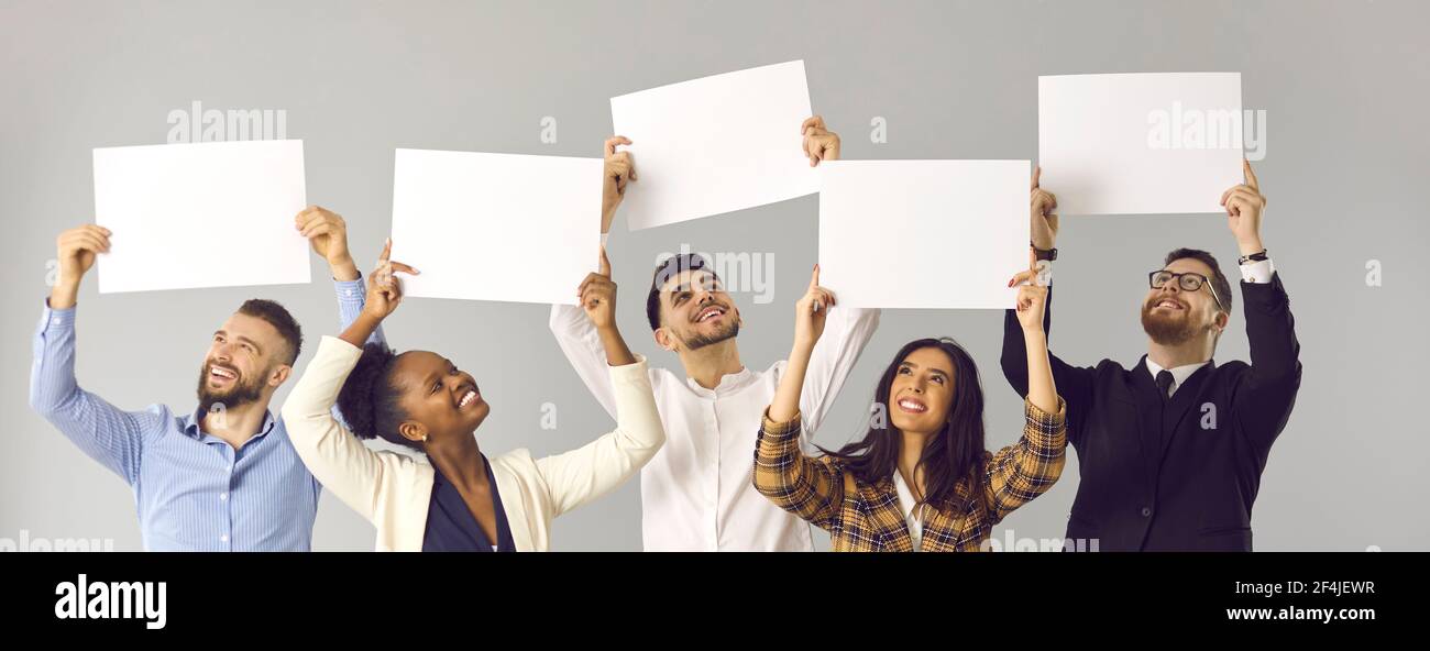 Groupe de gens multiraciaux heureux tenant des signes de maquette blanche arrière-plan studio gris Banque D'Images