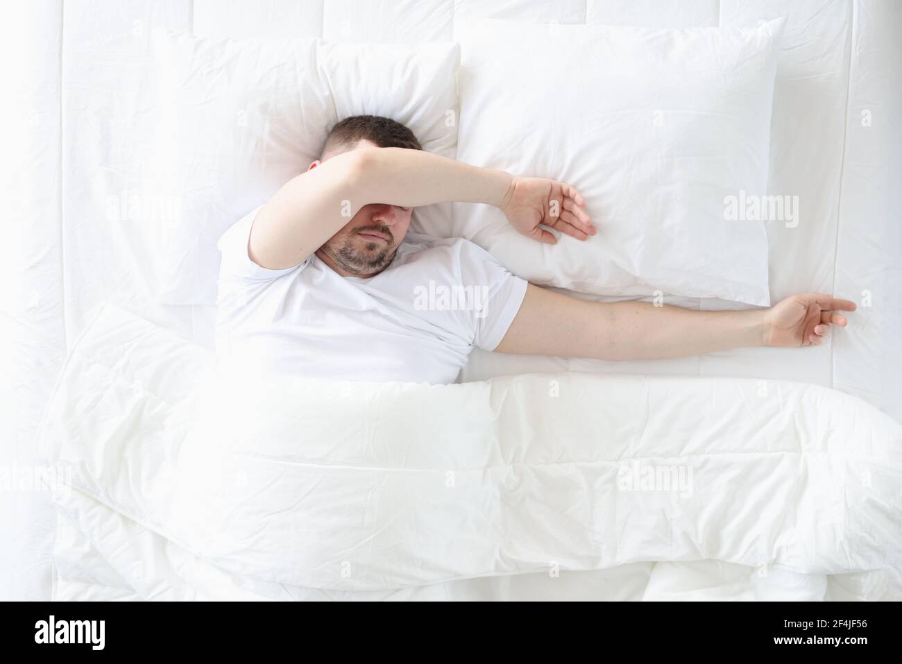Un homme adulte dort dans la chambre sur un grand lit Banque D'Images