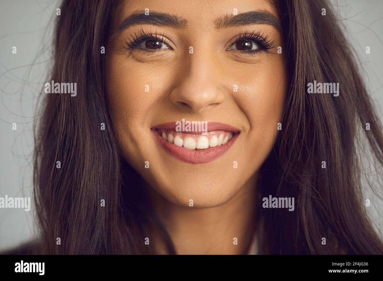 Portrait en gros plan de la jeune femme heureuse avec de longs cheveux foncés et un sourire éclatant ouvert Banque D'Images