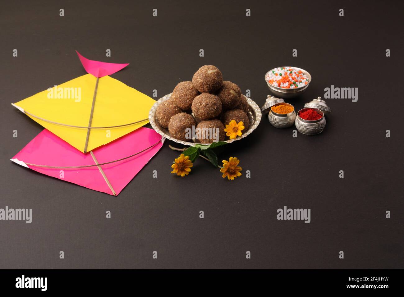 Til Gul OU Sweet Sesame Laddu avec Kite model, haldi Kumkum et cristaux de sucre pour le festival Makar Sankranti sur fond noir. Banque D'Images