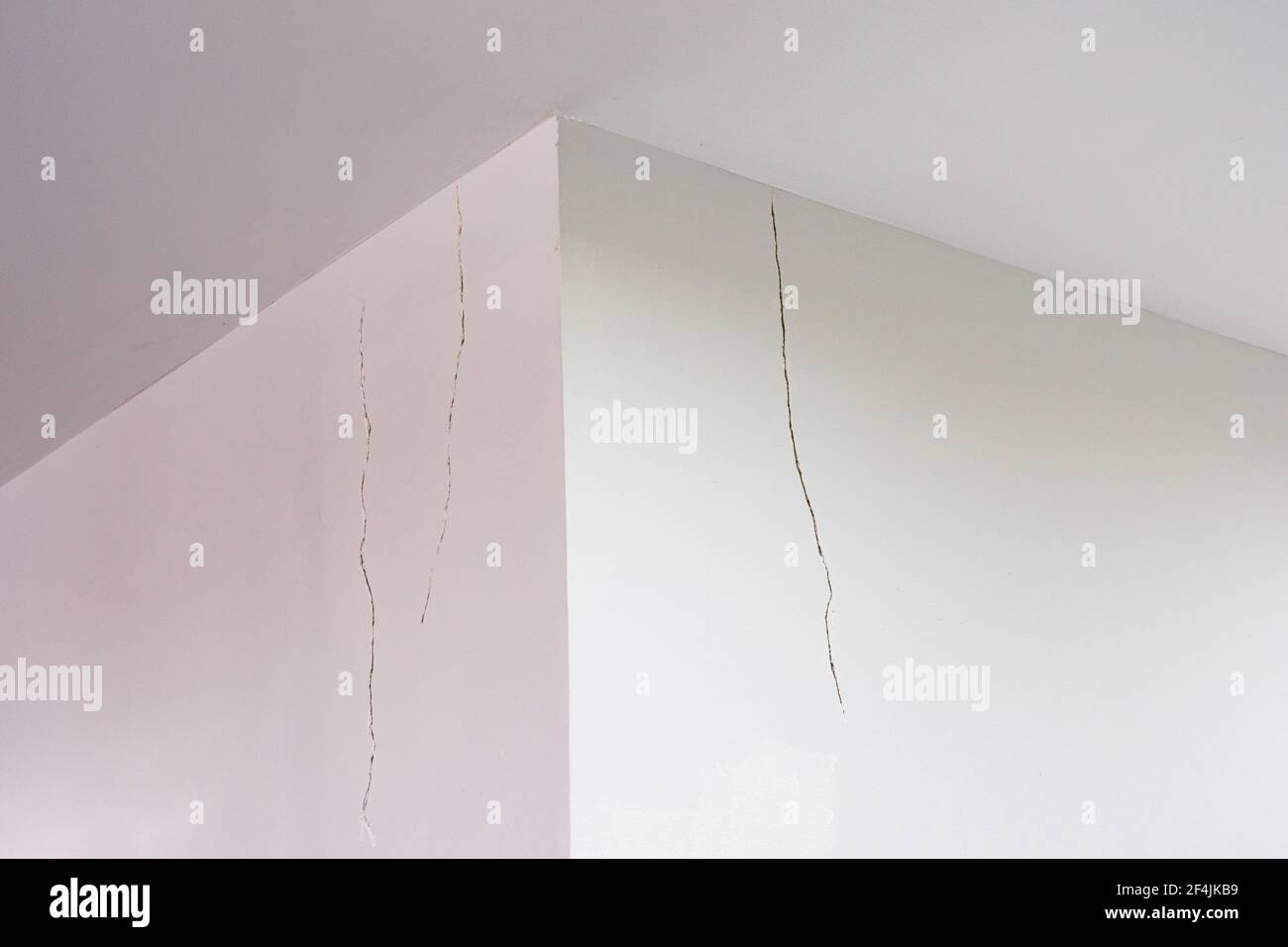 Mur en ciment peint en blanc avec rainures fissurées près du plafond Banque D'Images