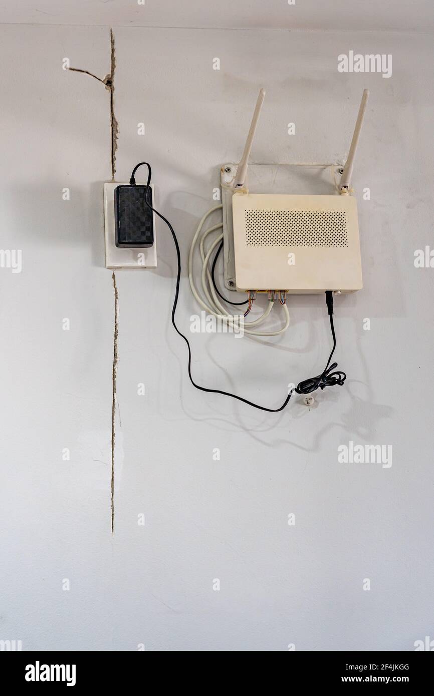 Photo verticale du modem wifi à côté d'un mur fissuré Banque D'Images