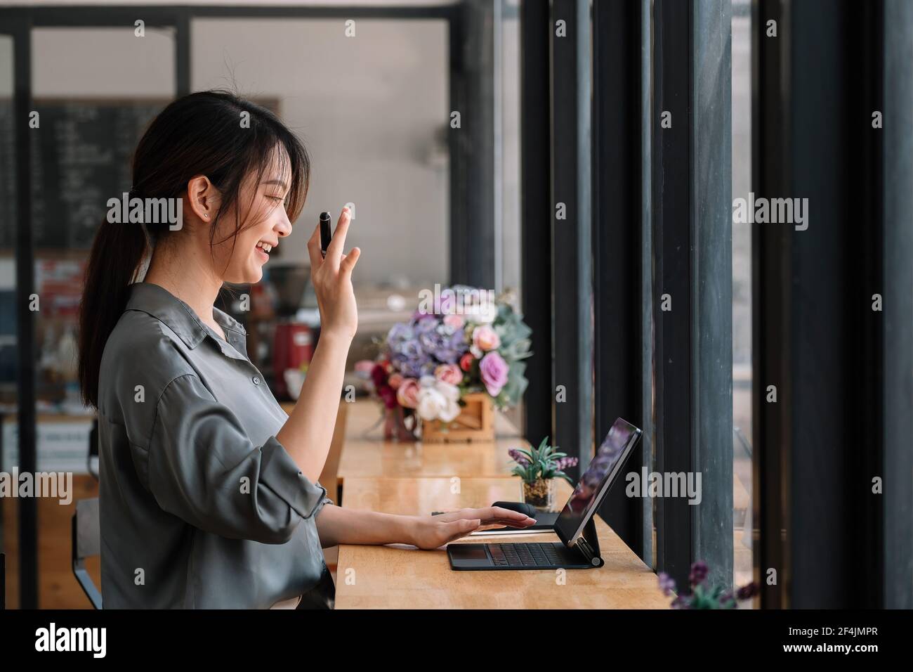 Communication par appel vidéo le leader asiatique parle à ses collègues de travail à domicile et porte des écouteurs lors d'une réunion virtuelle. L'étudiant utilise un ordinateur portable et Banque D'Images