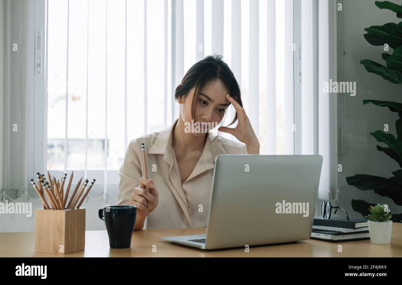 Portrait d'une femme d'affaires asiatique pensant et travaillant avec un ordinateur portable ordinateur au bureau Banque D'Images