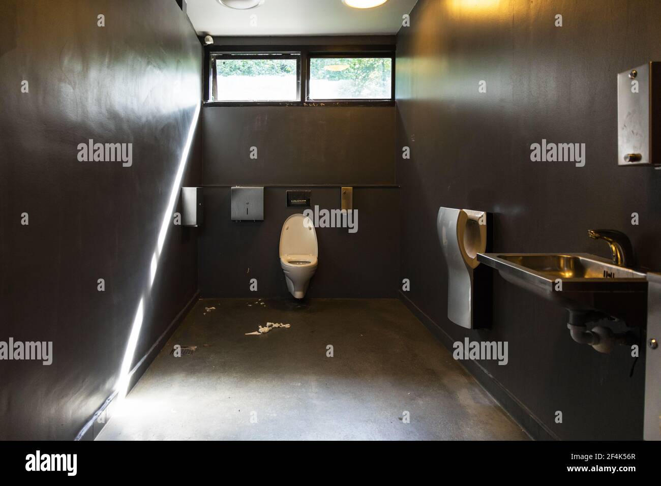 Papier toilette sur le sol dans une salle de bains sale Banque D'Images