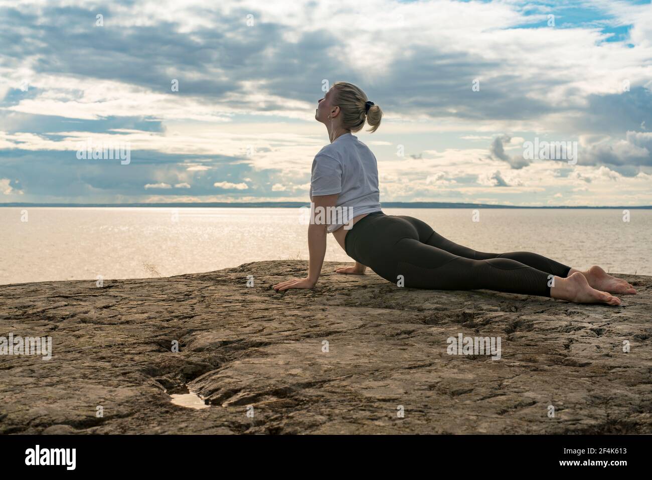 Femme pratiquant le yoga, la méditation ou s'étirant à côté de l'eau sur la falaise Banque D'Images