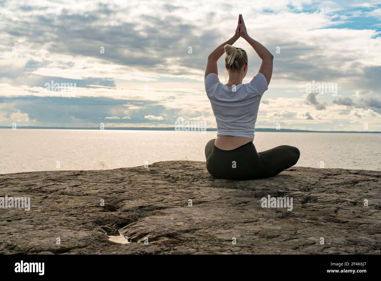 Femme pratiquant le yoga, la méditation ou s'étirant à côté de l'eau sur la falaise Banque D'Images