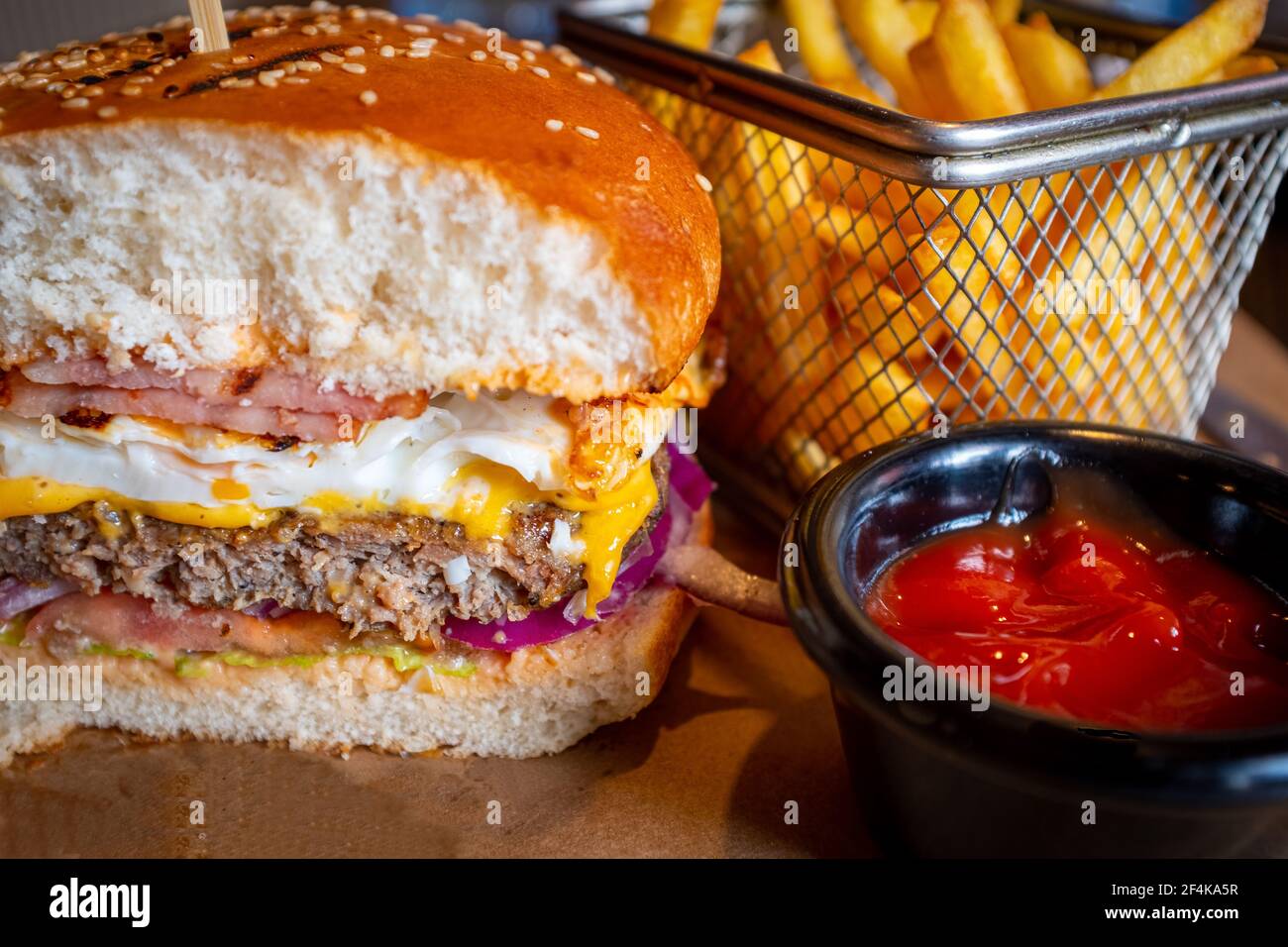 Hamburger de bœuf savoureux fait maison avec œufs, bacon et frites avec sauce tomate Banque D'Images
