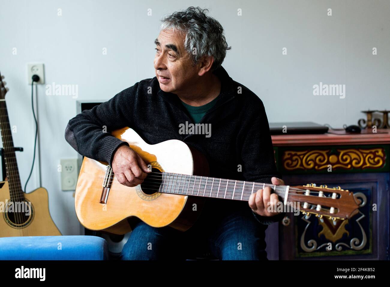 Tilburg, Pays-Bas. Middle aged man playing acoustic guitar dans son salon. Banque D'Images