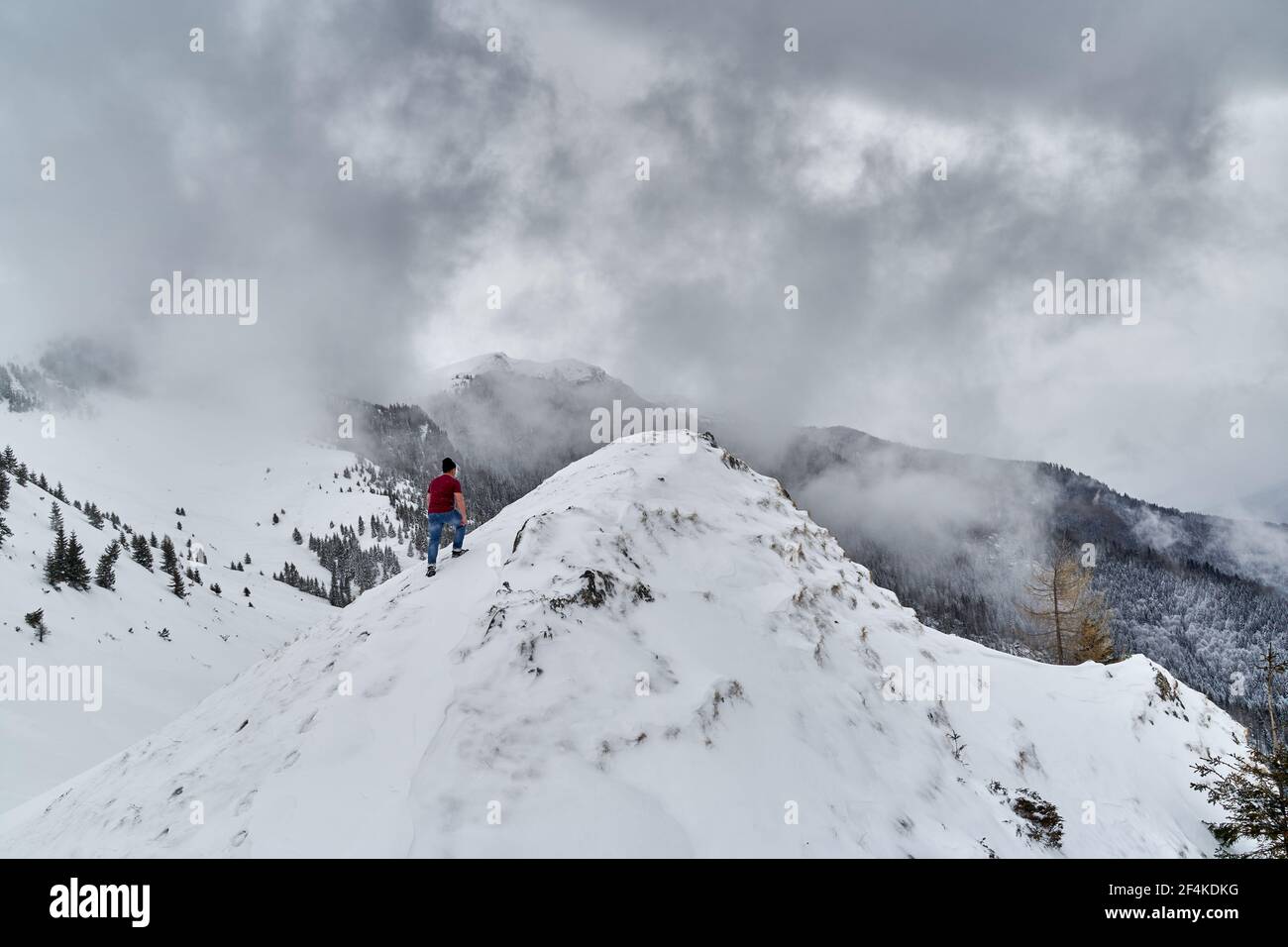 Homme en t-shirt escalade seulement une montagne à travers le blizzard en hiver Banque D'Images