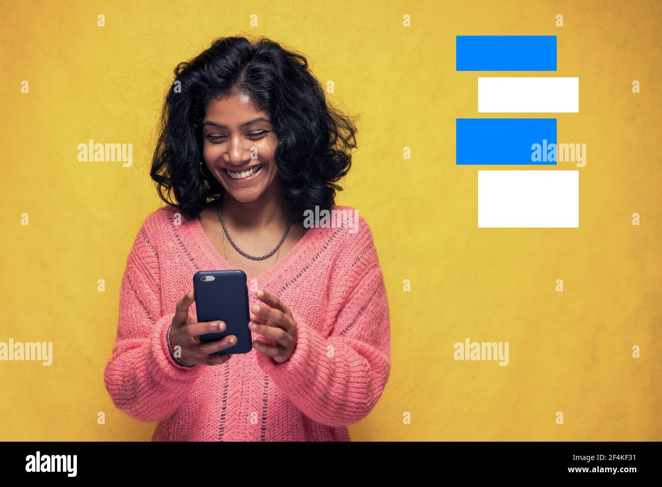 Belle fille Sri Lanka fait la technologie pose avec jaune vif Contexte - jeune femme utilise le téléphone mobile pour discuter et messagerie Banque D'Images