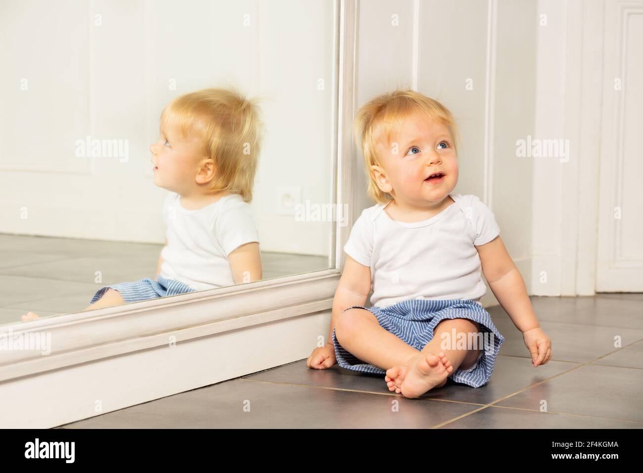 Portrait d'un tout-petit garçon assis à côté d'un grand miroir Banque D'Images