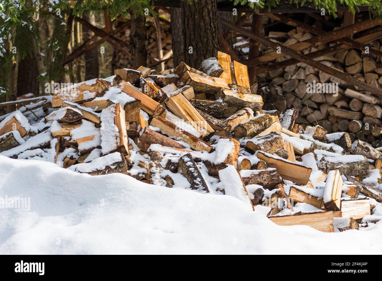 Pile ou pile composée de blocs, morceaux ou billes de bois en hiver ou au printemps avec de la neige. Gerbage de bois pour le séchage et le stockage Banque D'Images