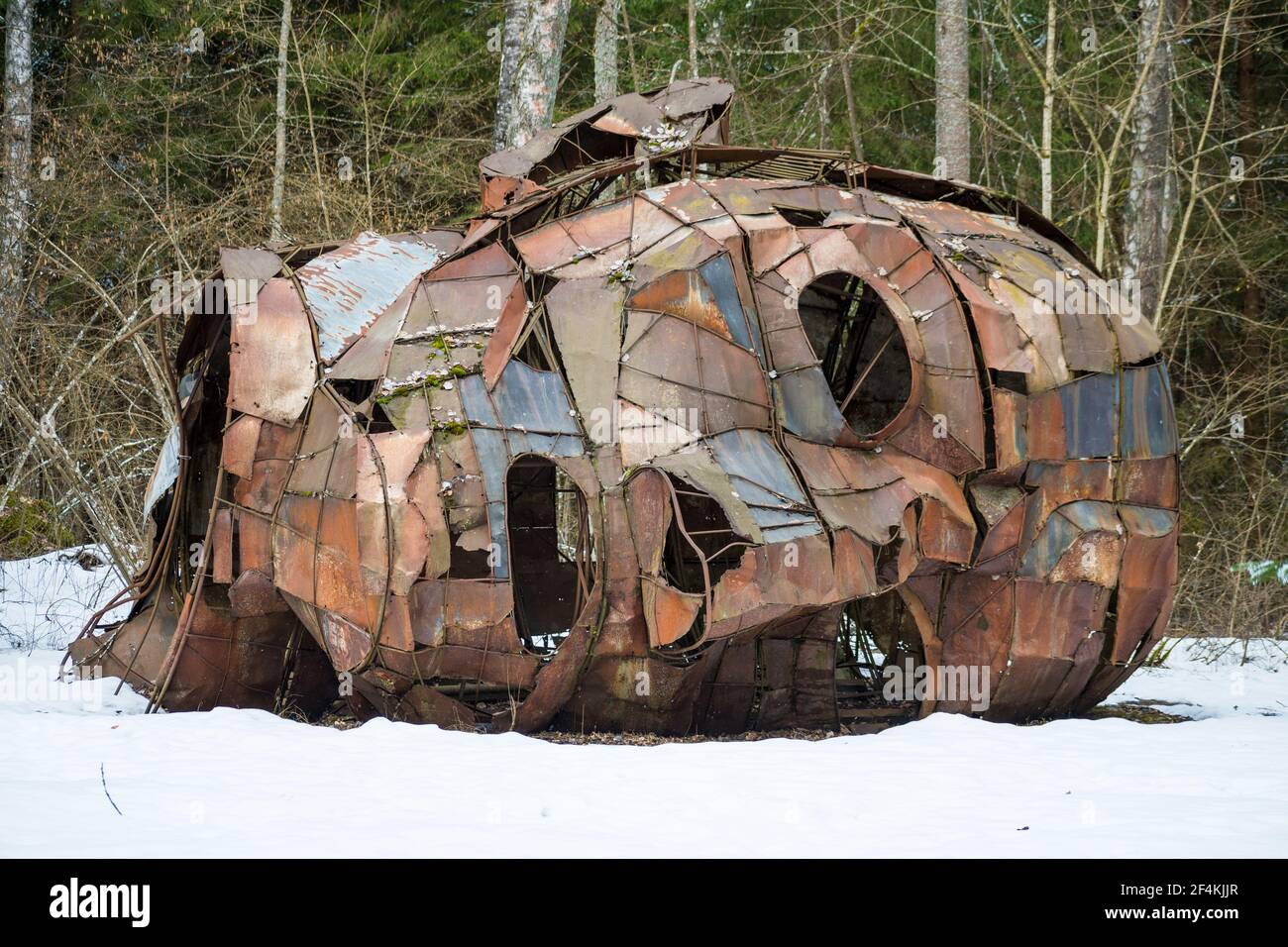 Homme créepy face dans un bois couché sur la neige, sculpture en fer rouillé Banque D'Images
