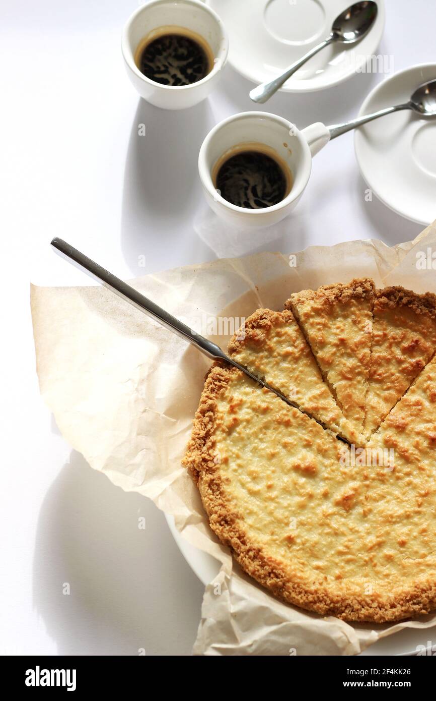 Dessert au fromage coupé en tranches avec deux tasses d'espresso servies sur du blanc. Concept de desserts faits maison. Banque D'Images