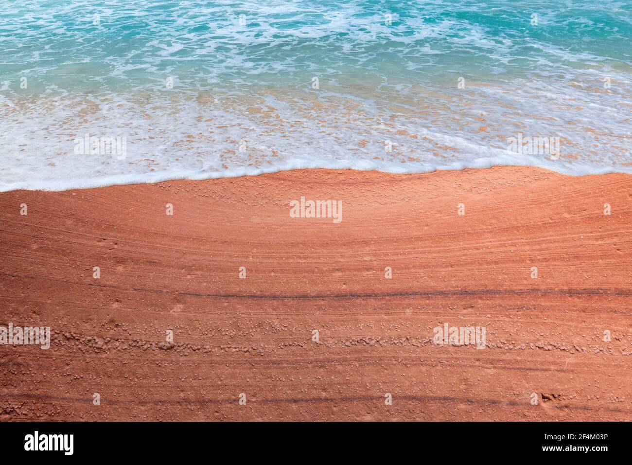 Plage en pierre rouge et vague bleue Banque D'Images