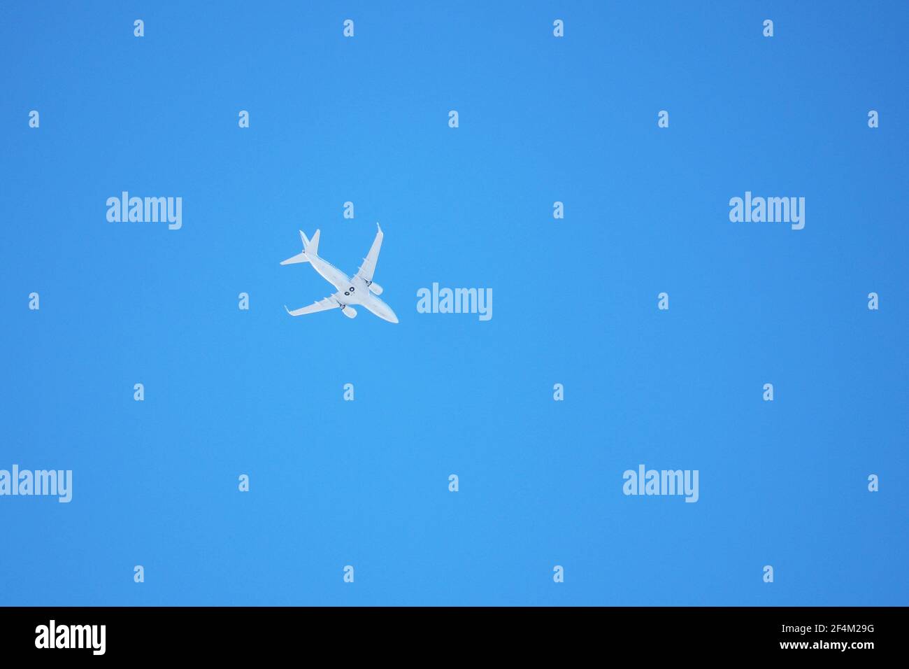 Avion blanc volant dans le ciel bleu clair. Plan commercial, vue de dessous Banque D'Images