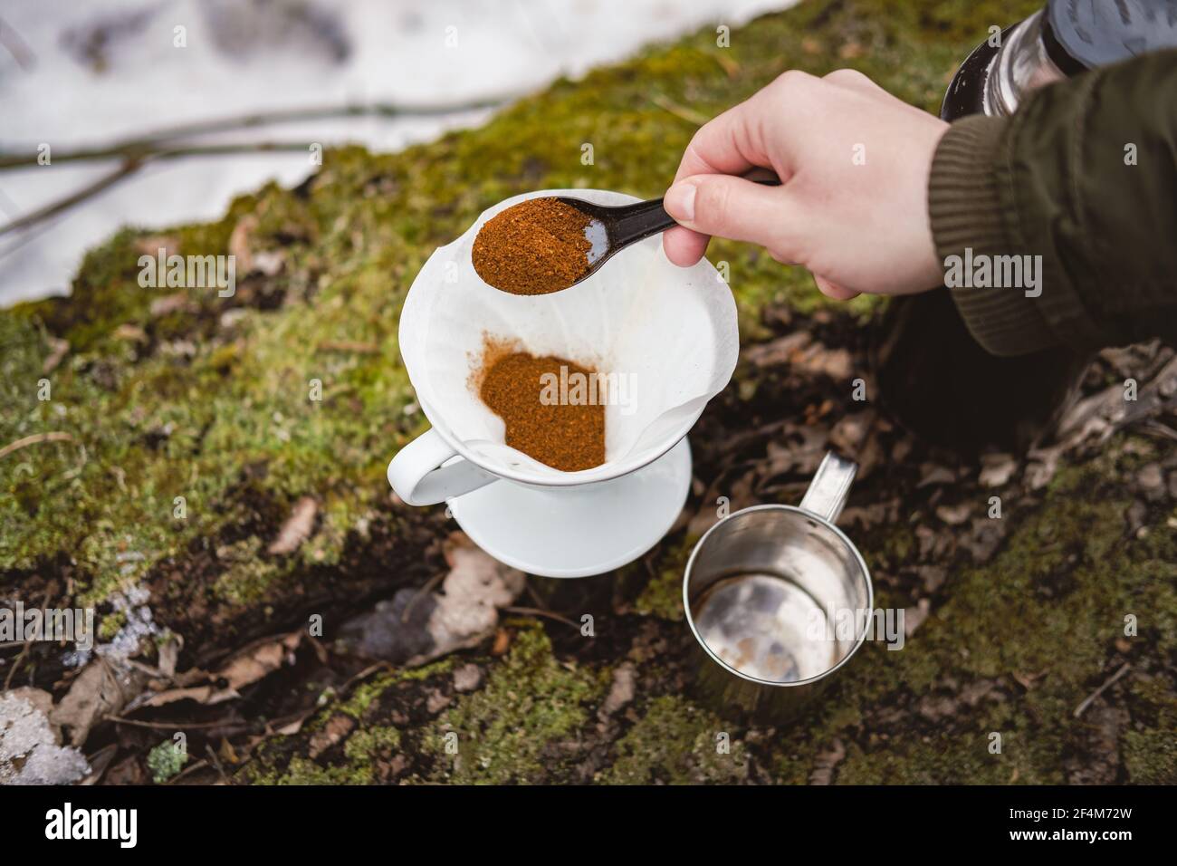 Faire couler le café à l'extérieur lors d'une randonnée. Versez à la main  du café moulu dans un filtre en papier pour préparer le café Photo Stock -  Alamy